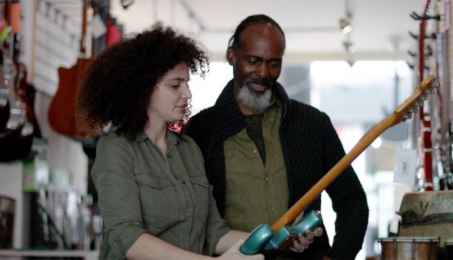 A man and woman looking at a guitar in a store